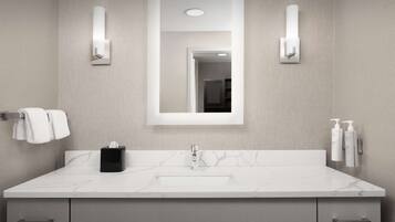 A modern bathroom with a marble sink, a large mirror, and two wall-mounted light fixtures.