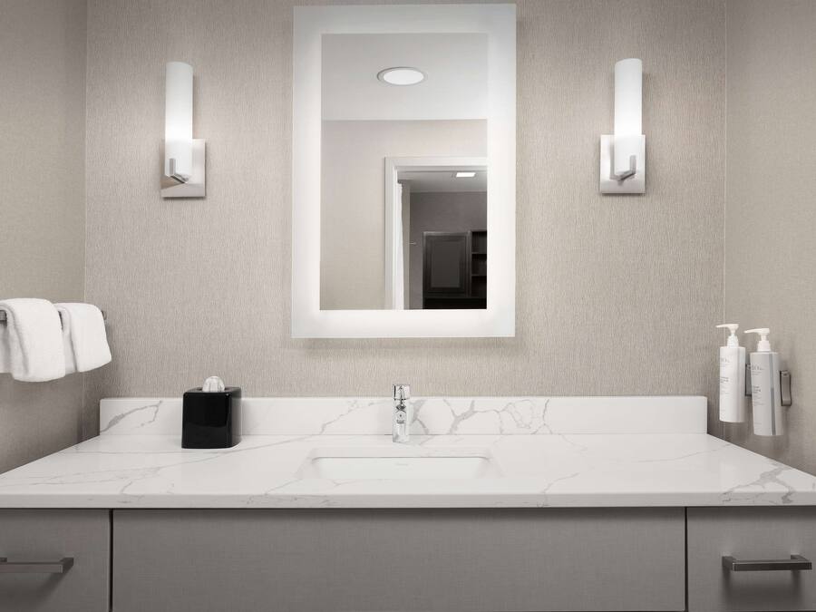 A modern bathroom with a marble sink, a large mirror, and two wall-mounted light fixtures.