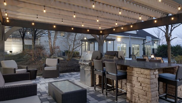 An outdoor patio with wicker furniture, a stone bar, and a grill.