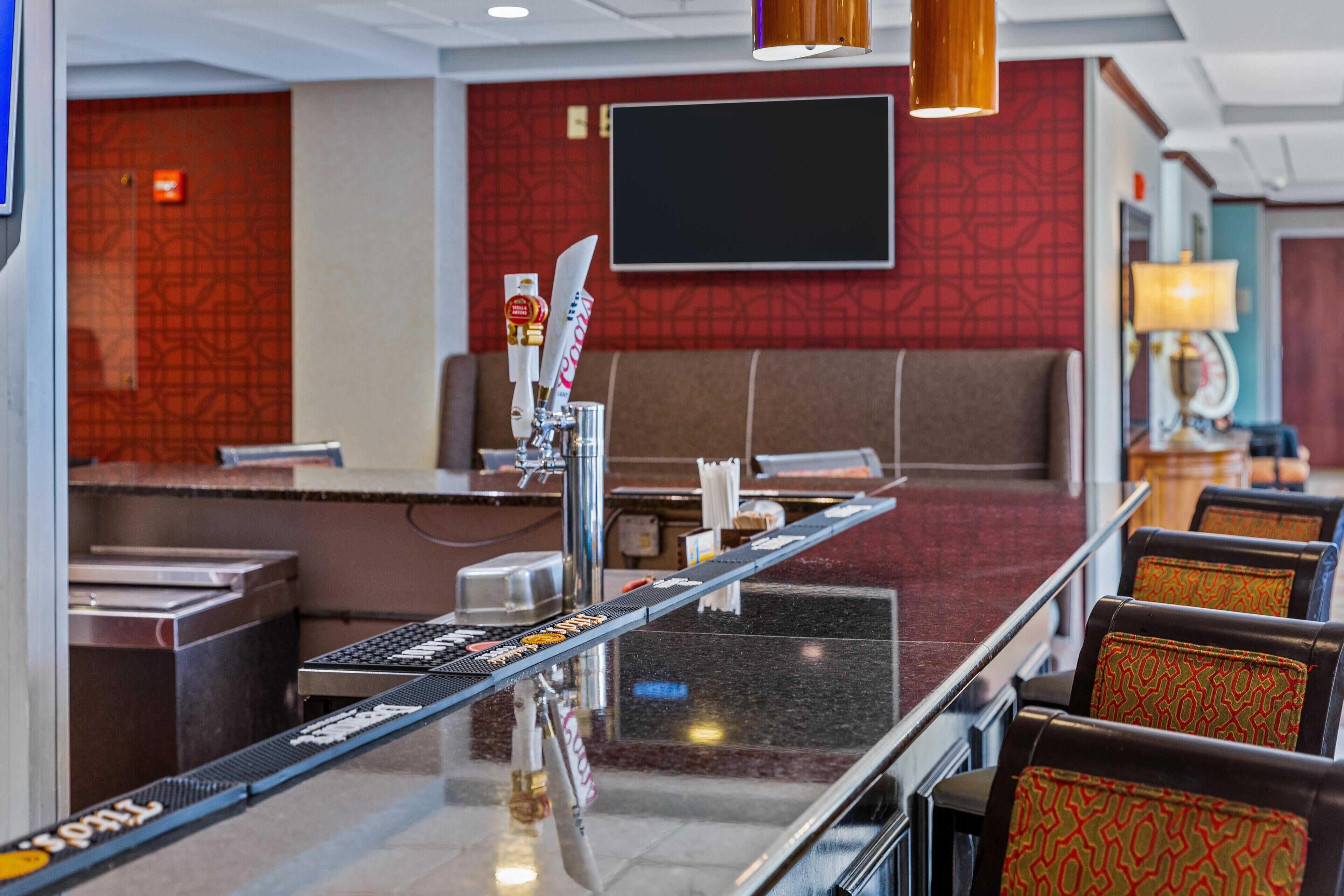 A hotel lobby with a reception desk, seating area, and a large flat-screen TV mounted on the wall.