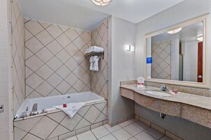 Un baño con bañera, lavamanos, espejo y toallero.