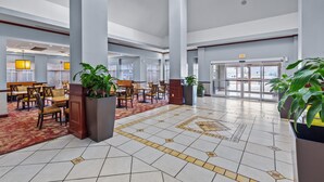 Eine großzügige Lobby mit hohen Decken, einem gemusterten Fliesenboden und mehreren Sitzbereichen.