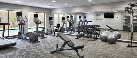 A gym with treadmills, weight machines, and exercise balls.