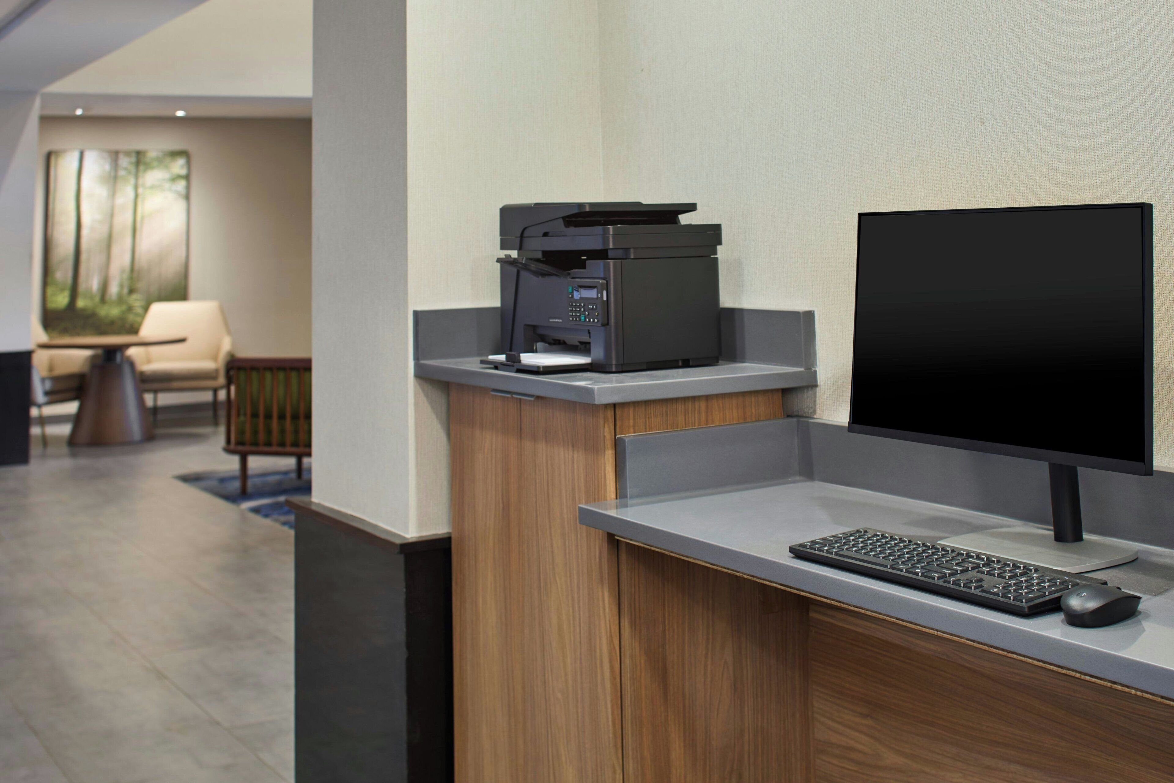 A reception desk with a printer, a computer monitor, a keyboard, and a mouse.