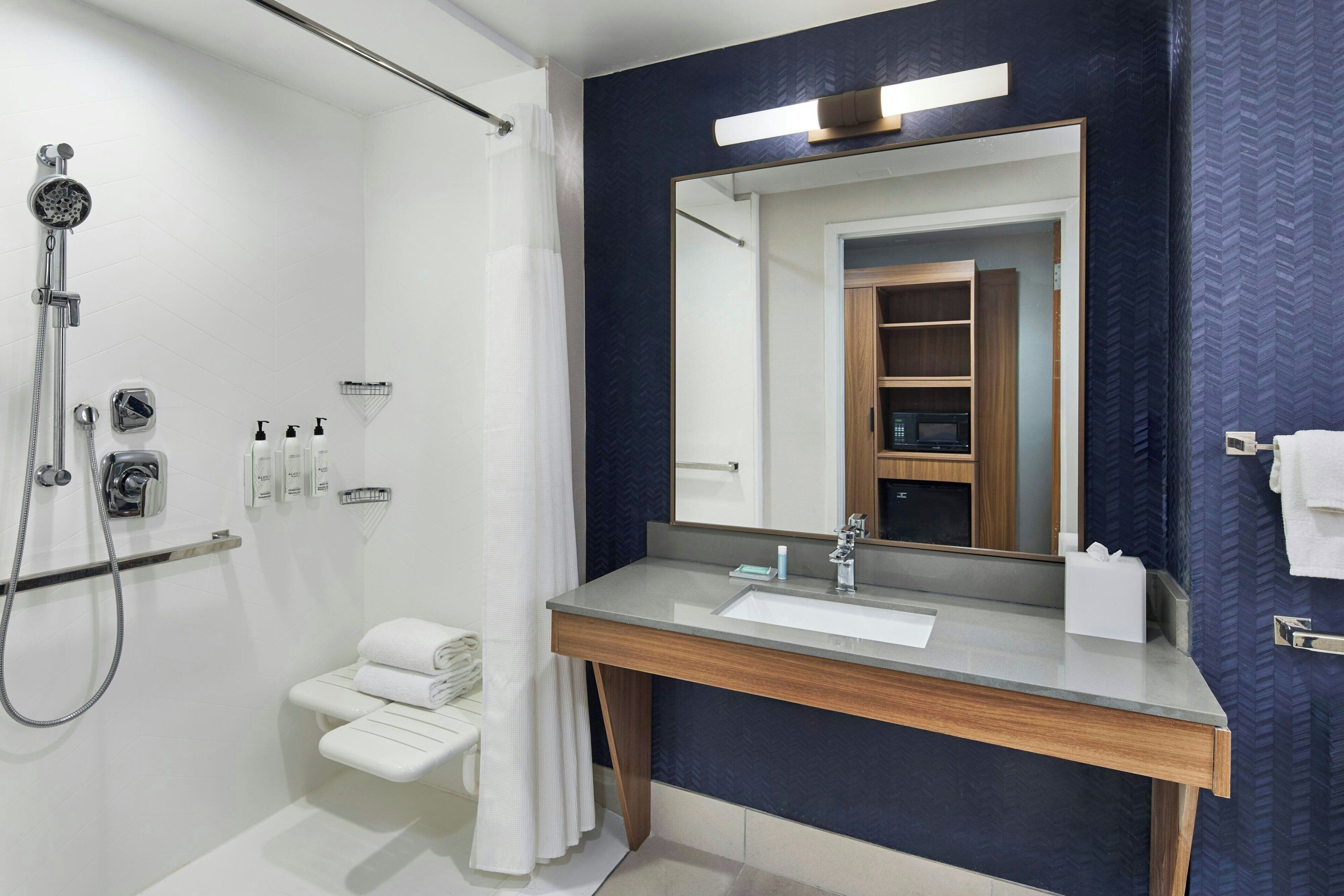 A modern bathroom with a shower, a sink, and a mirror.