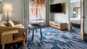Een hotelkamer met een sofa, een tafeltje, een televisie, een bureau en een bed.