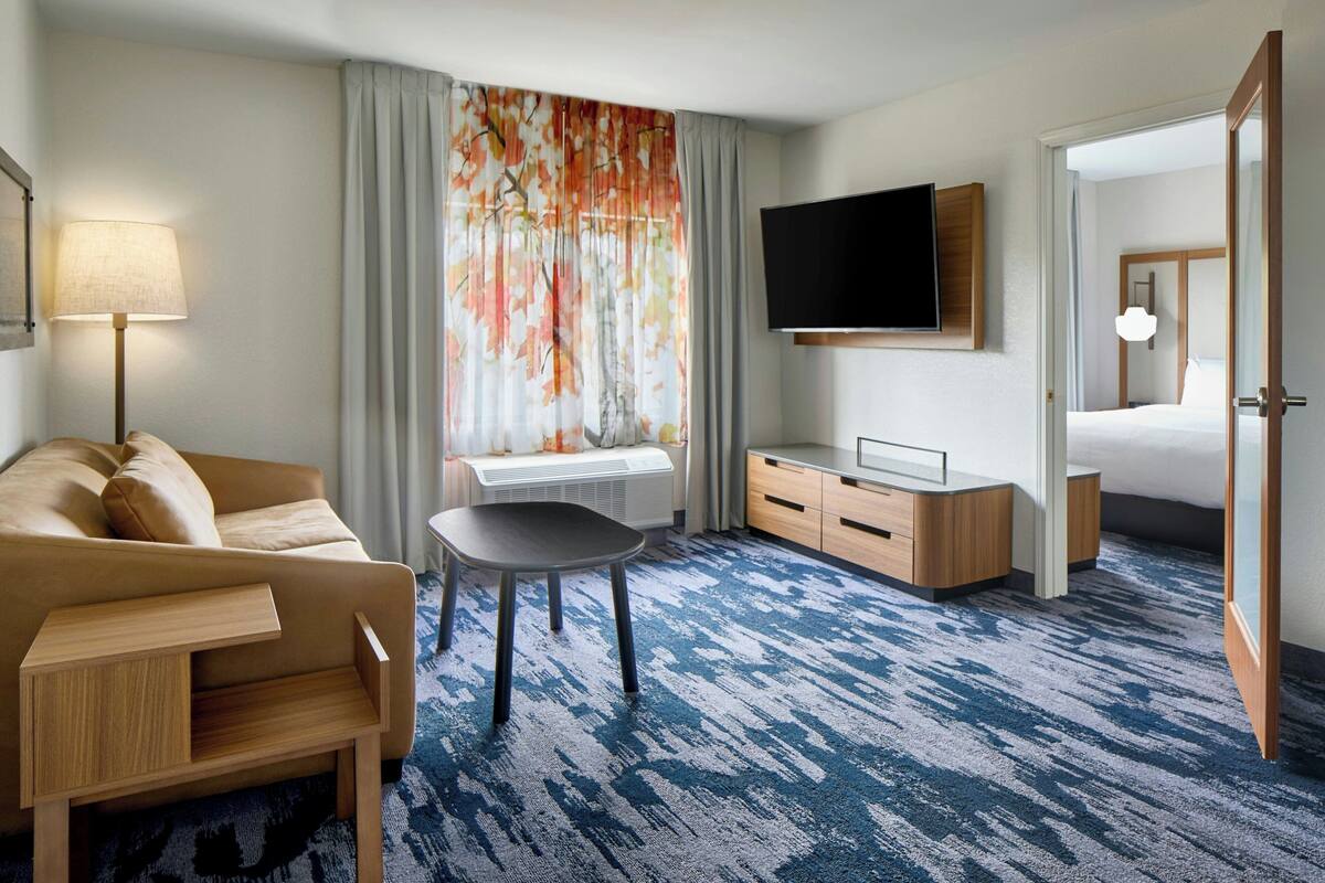 Une chambre d’hôtel avec un canapé, une petite table, une télévision, un bureau et un lit.