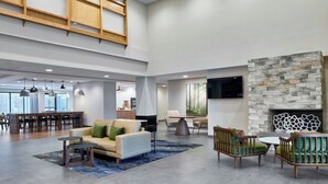 Een ruime lobby met een hoog plafond, een stenen open haard, modern meubilair en een eetgedeelte.