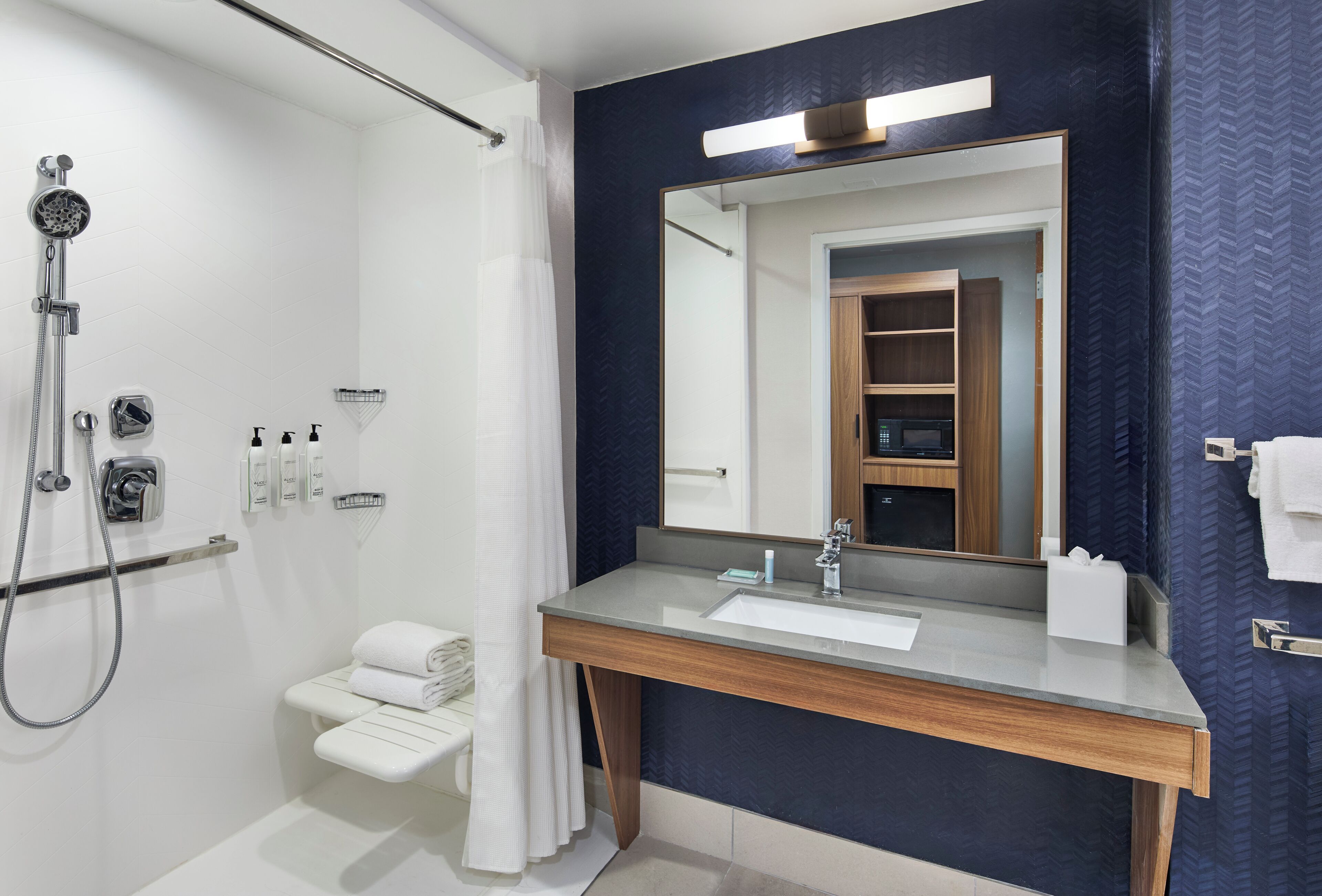 A modern bathroom with a shower, a vanity with a mirror, and a towel rack.
