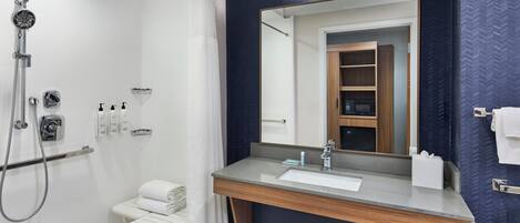A modern bathroom with a shower, a vanity with a mirror, and a towel rack.
