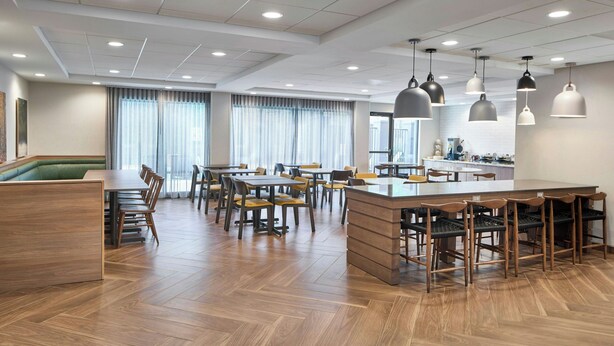 Een ruime hotel lobby met een centraal eiland, meerdere zithoeken en een keuken op de achtergrond.