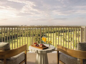 A balcony with a table set for two, overlooking a golf course.