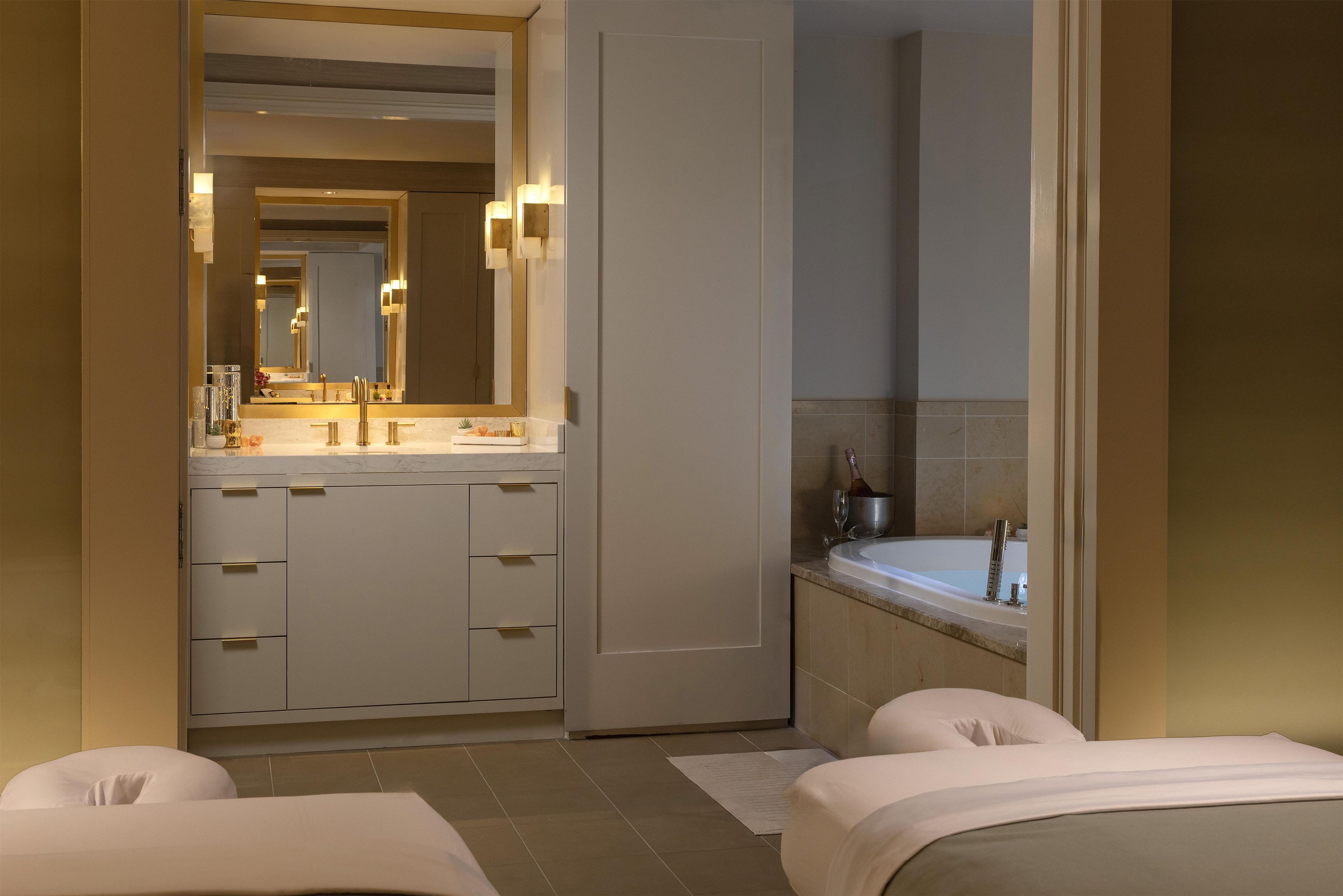 A modern bathroom with a large mirror, a bathtub, and a vanity with a sink.