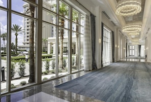 A spacious corridor with large windows, a polished floor, and a grand chandelier. - Waldorf Astoria Orlando - An Official Walt Disney World® Hotel (Orlando)