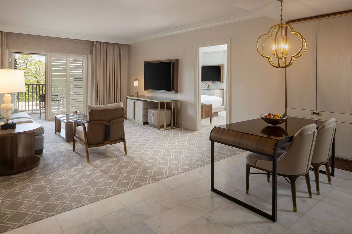Une chambre d’hôtel moderne dotée d’un coin repas, d’une télévision et d’un balcon.