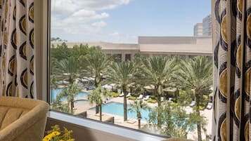 Quarto de hotel com vista para a área da piscina, incluindo palmeiras e espreguiçadeiras.