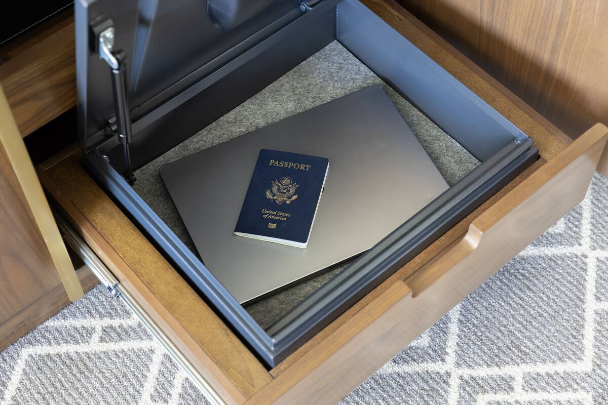 Un tiroir contenant une valise fermée et un passeport posé dessus.