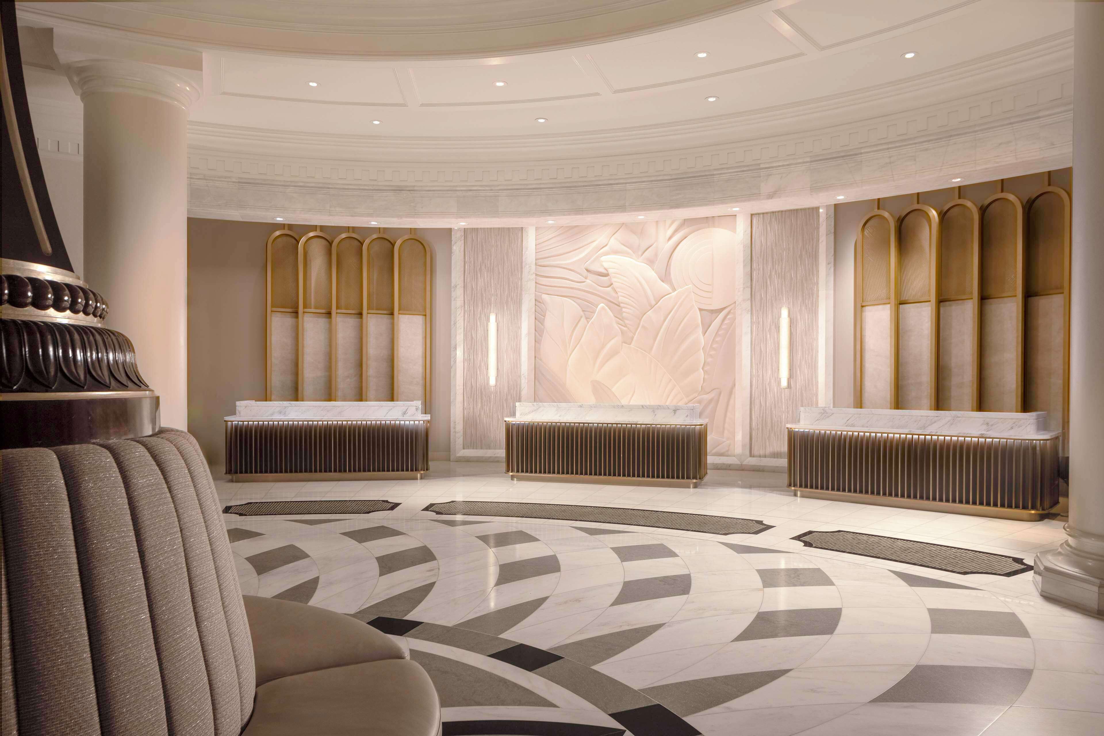 A luxurious lobby with marble flooring, elegant seating, and a central reception area with a marble counter.