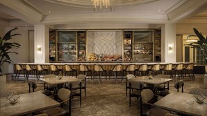 A bar area with multiple seating options, a marble countertop, and a decorative ceiling light.