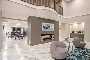 A spacious lobby with a marble floor, a fireplace, and modern seating.