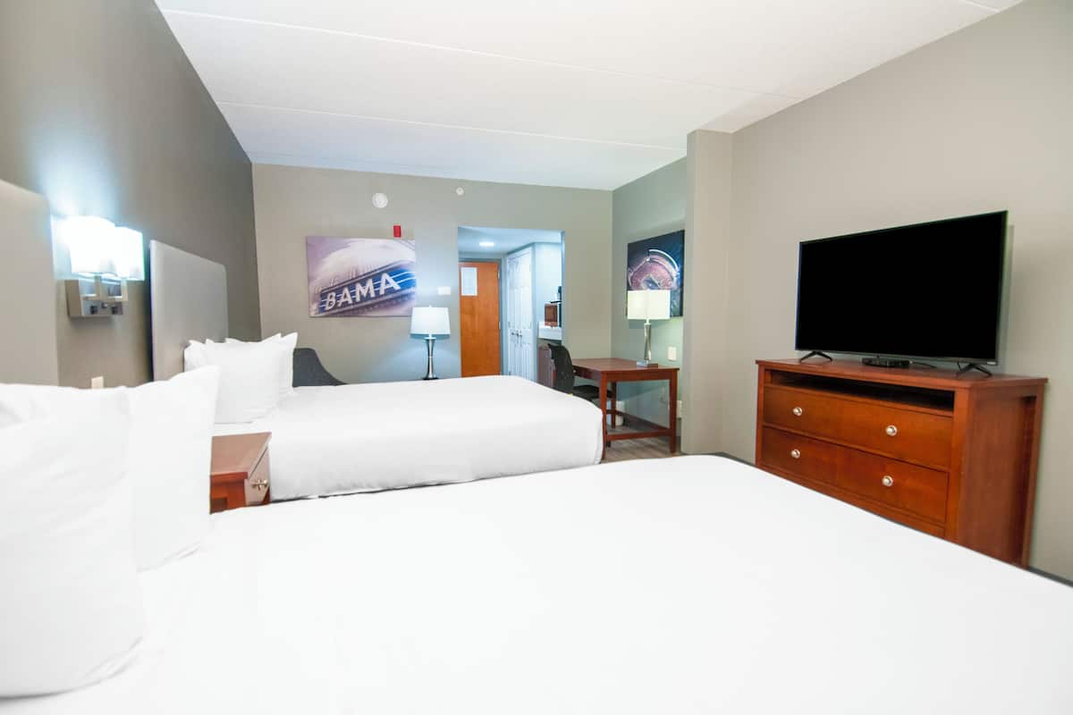 Une chambre d’hôtel avec deux lits, une télévision, un bureau et une lampe.