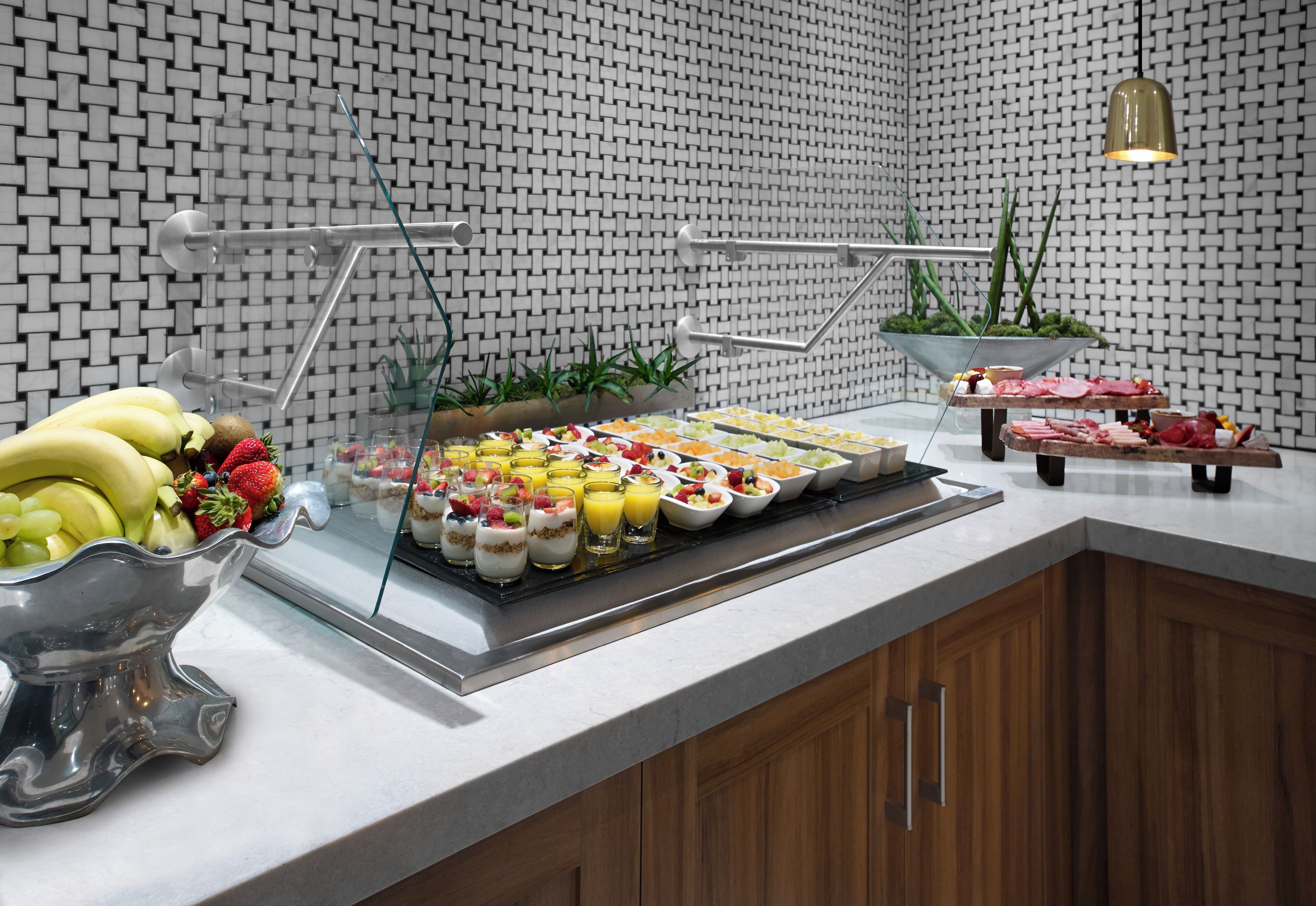 A buffet with various food items and a fruit bowl.