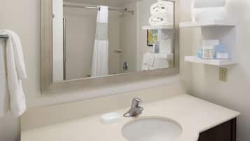 A bathroom with a sink, mirror, towel rack, and shelves with toiletries.