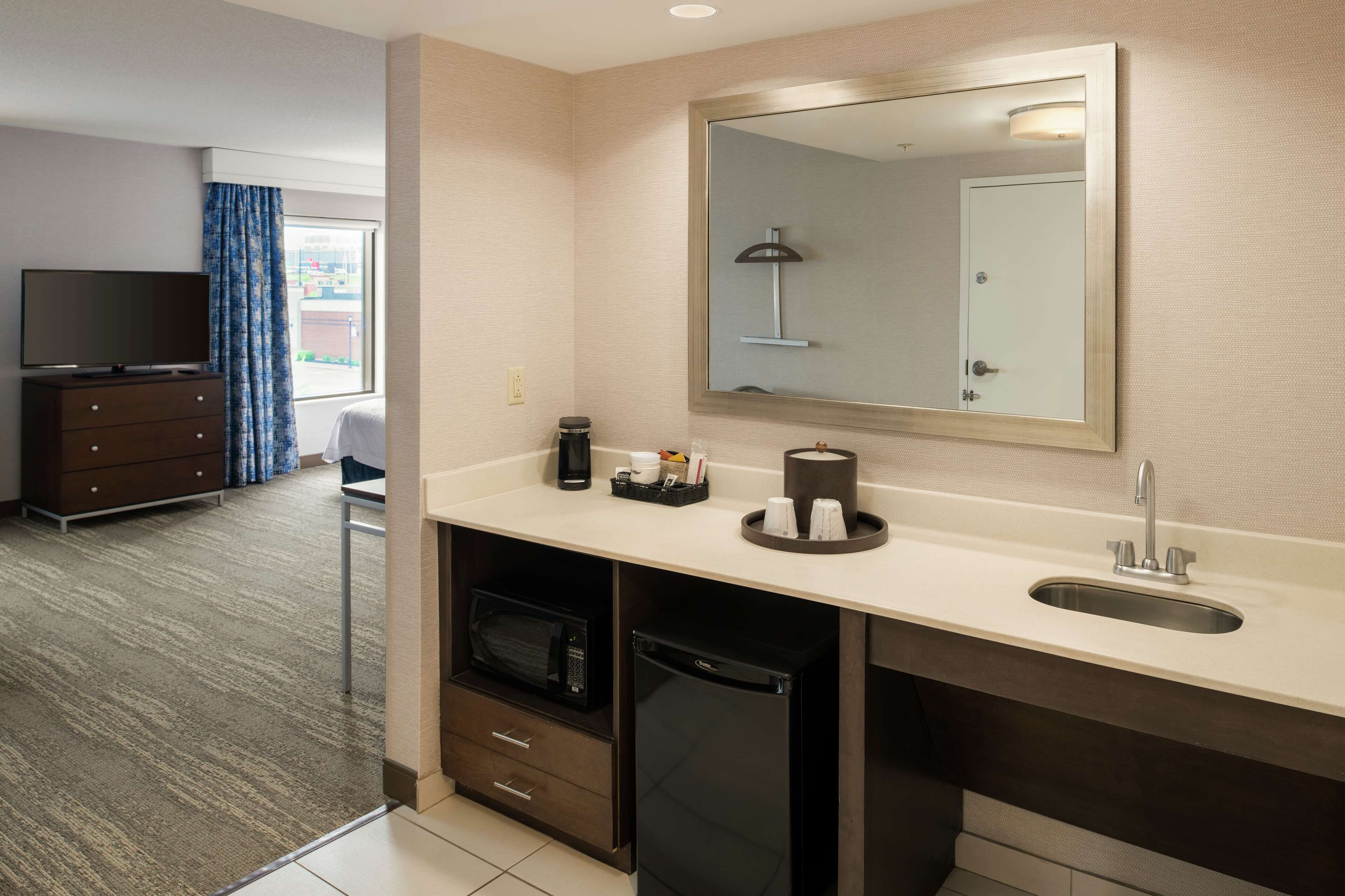 Een hotelbadkamer met een wastafel, spiegel en een magnetron.