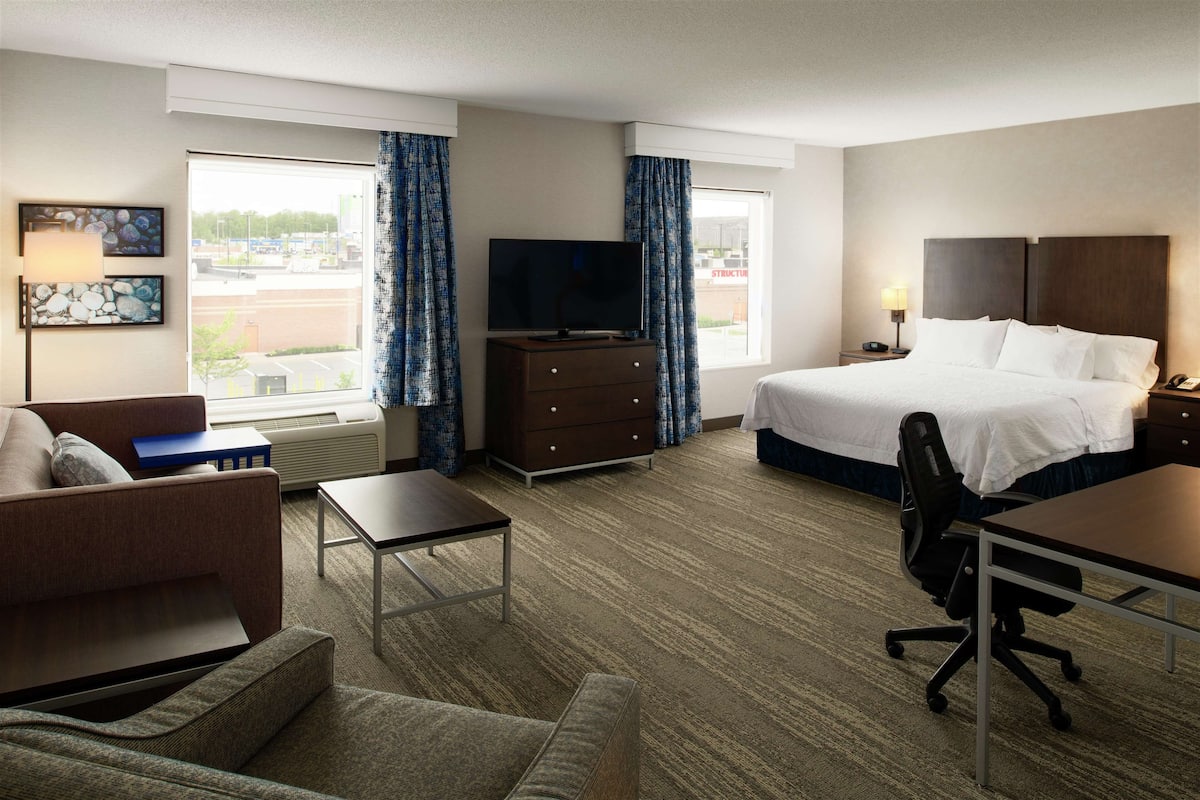 Ein Hotelzimmer mit Bett, Schreibtisch, Sessel, Fernseher, Kommode und einer Couch.
