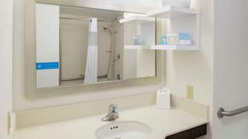 Une salle de bain équipée d’un lavabo, d’un miroir, d’une douche et d’un porte-serviettes.