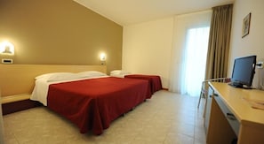 Habitación de hotel con dos camas, un escritorio con ordenador y una ventana con cortinas.