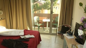 A hotel room with a bed, a desk with a computer, a chair, and a view of the outside. - Hotel Elvezia (Pesaro)