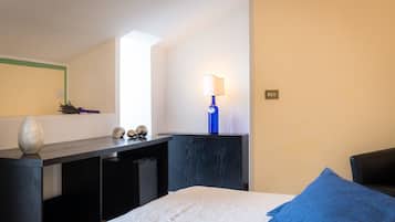 A bedroom with a bed, a desk, a lamp, and a window.