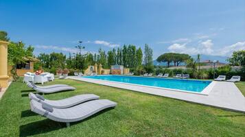 A swimming pool with lounge chairs, a small bar area, and a view of trees and mountains.