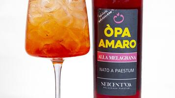 Una botella de BeVilo BeVincio Opa Amaro con etiqueta y un vaso de la bebida con hielo.