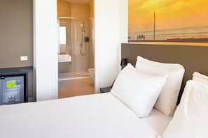 Une chambre d’hôtel avec un lit, une télévision, une douche et un tableau représentant une scène de plage.