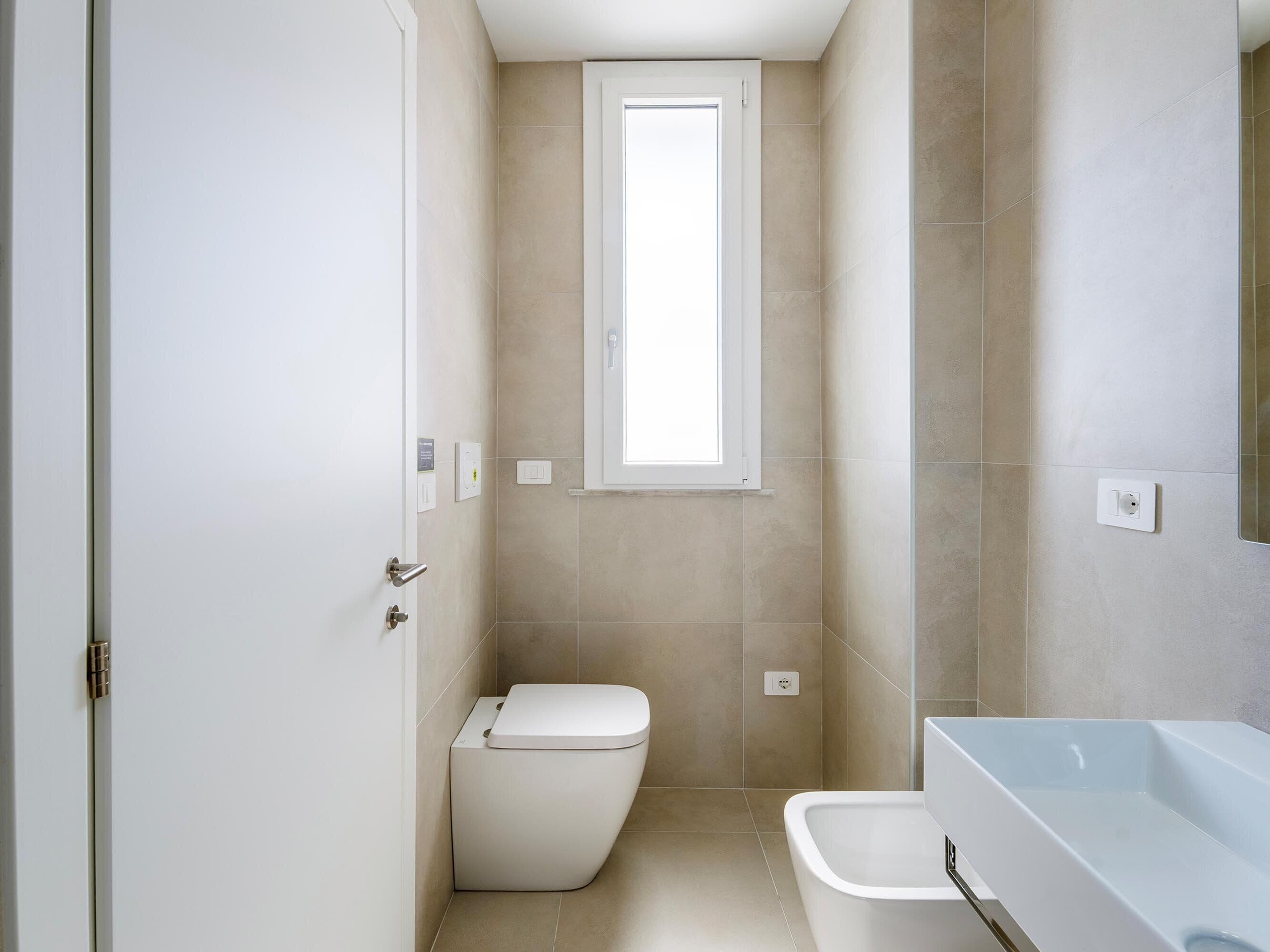 A modern bathroom with a toilet, a sink, and a window.