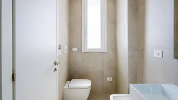 A modern bathroom with a toilet, a sink, and a window.