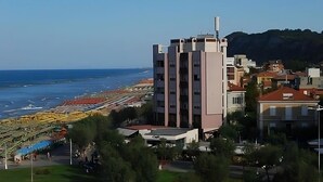 Un edificio alto con varios pisos, ubicado cerca de una playa con costa rocosa.