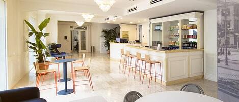 A modern hotel lobby with a bar area, seating arrangements, and a large potted plant.