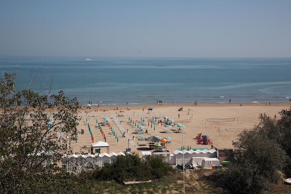 Ein Strand mit Sonnenschirmen, Liegen und einem Volleyballnetz.