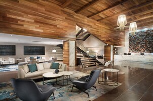 Un vestíbulo amplio con techo de madera, una escalera y una mesa de recepción.