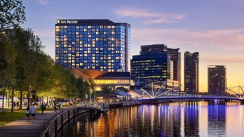 A modern cityscape with a prominent Pan Pacific hotel, a bridge, and a waterfront promenade.