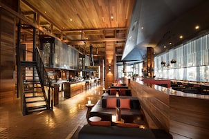 Un interno moderno con soffitto in legno, angolo bar, posti a sedere e una scala.