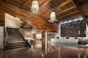 Una hall moderna con soffitto in legno, una reception in marmo e una scala.
