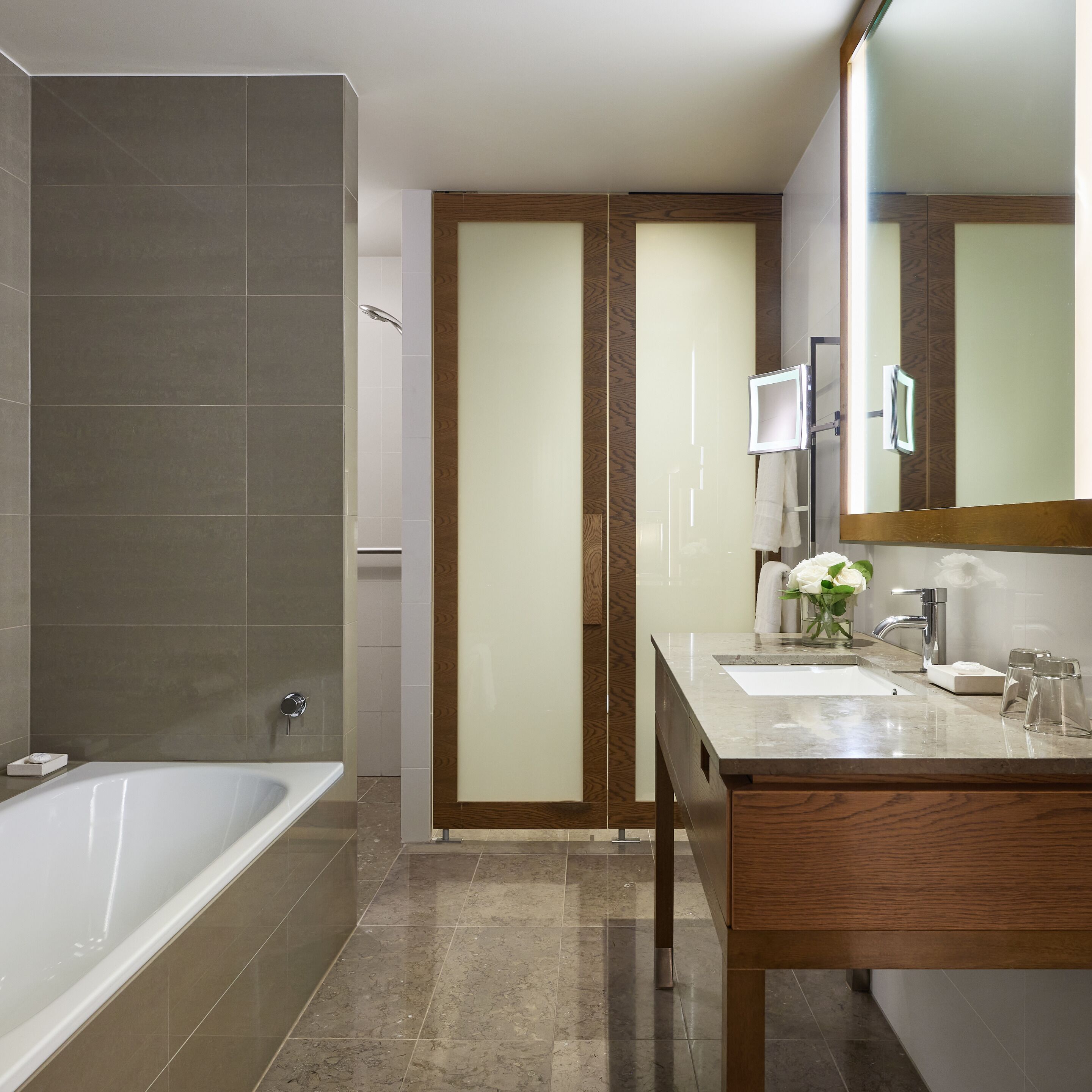 A modern bathroom with a bathtub, a vanity with a mirror, and a shower area.