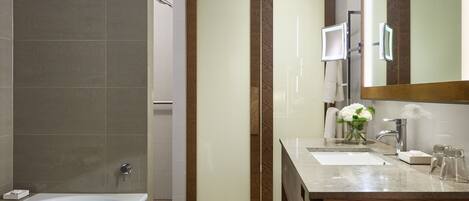 A modern bathroom with a bathtub, a vanity with a mirror, and a shower area.