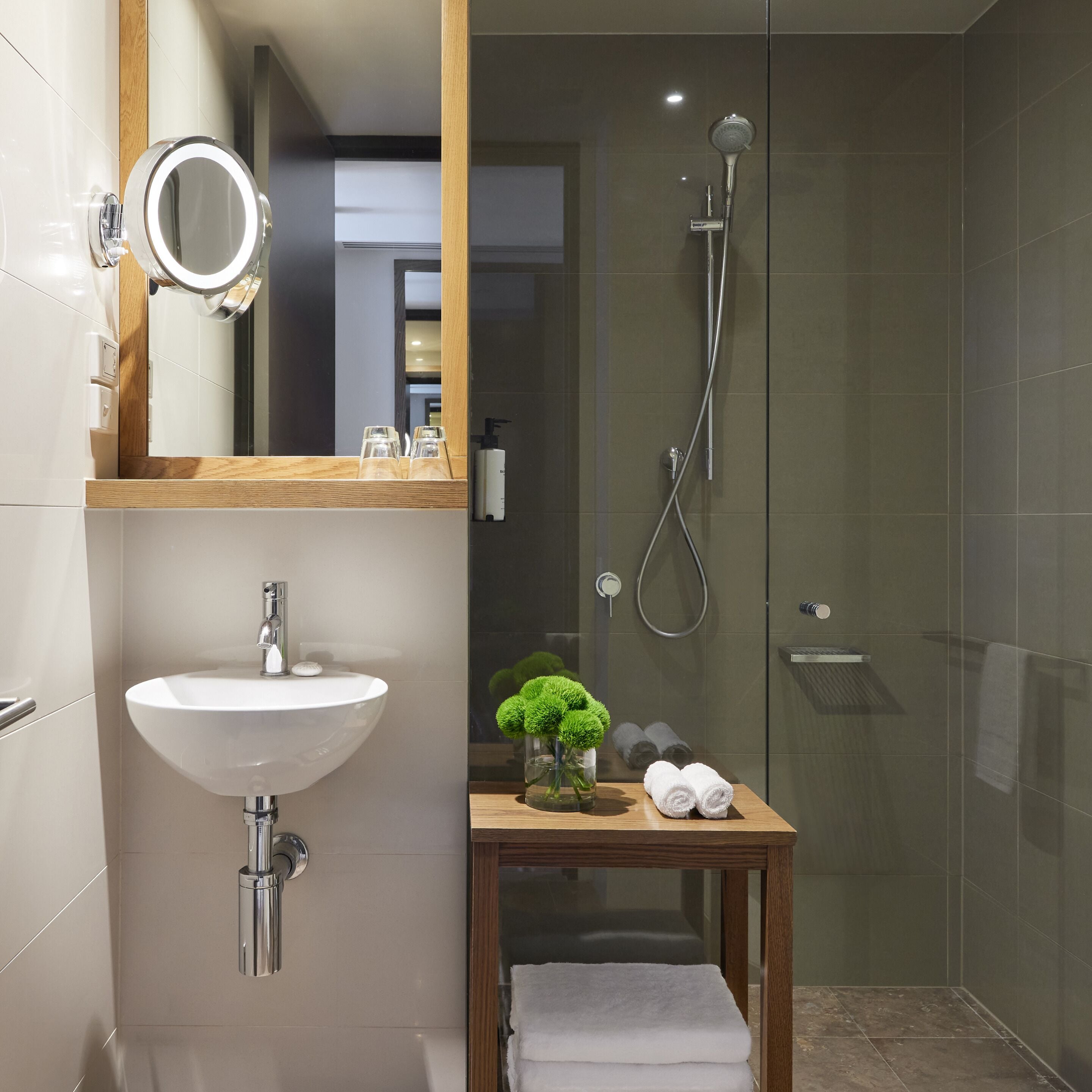 Un baño moderno con lavamanos, espejo y ducha.