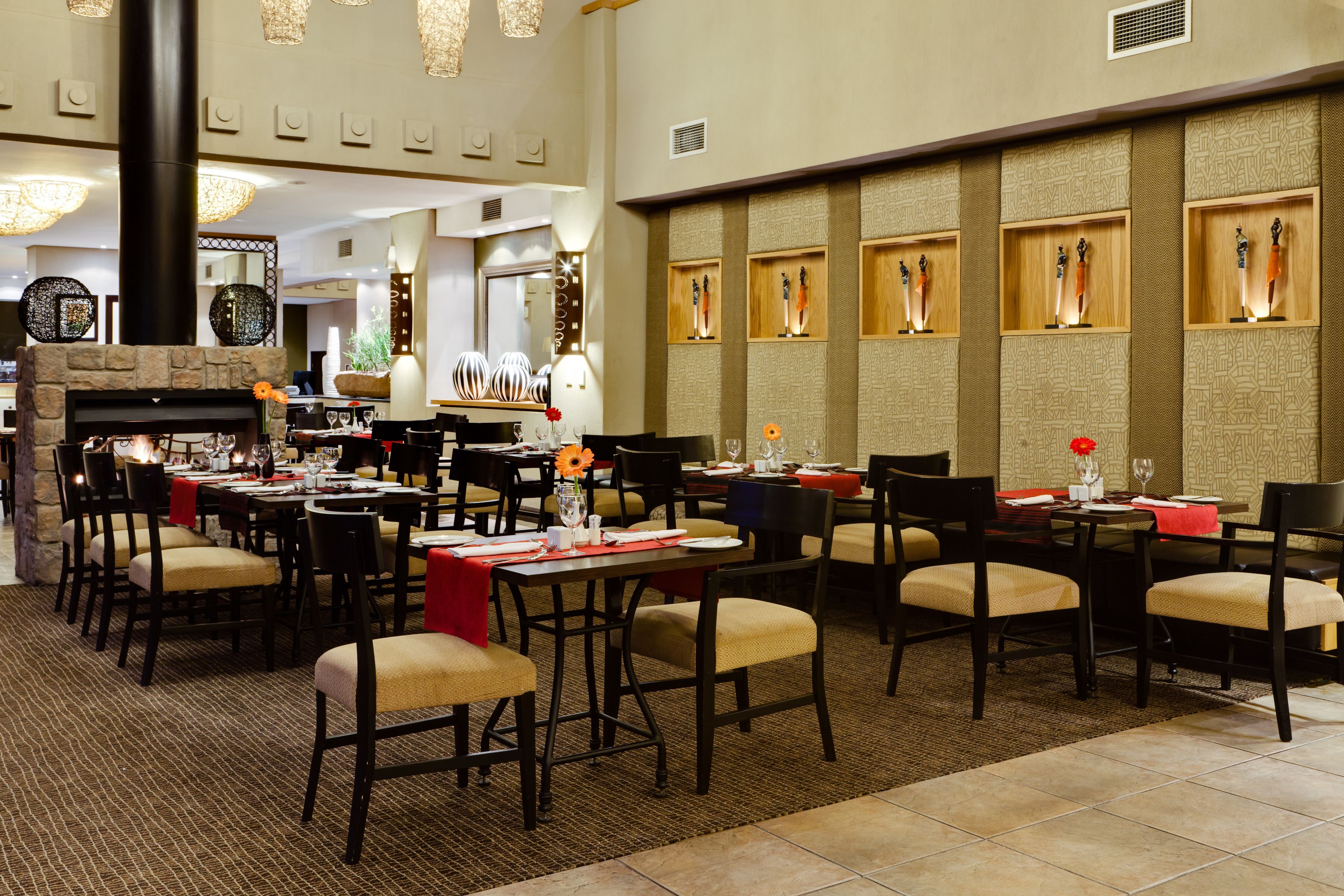 Un restaurante con varias mesas y sillas, una chimenea y paneles decorativos en las paredes.
