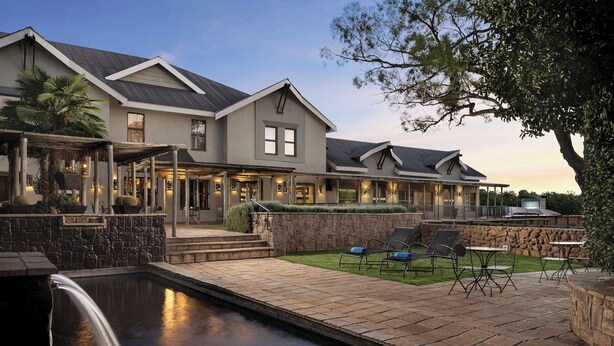 Una casa grande con piscina, mobiliario exterior y una cascada.